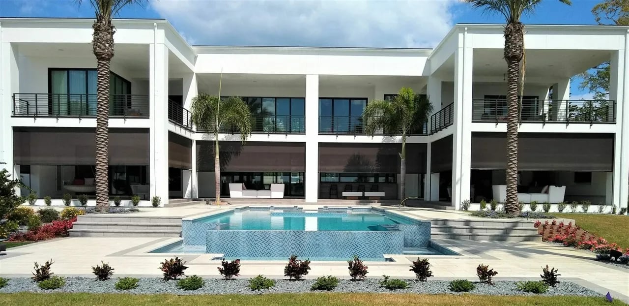 Modern white two-story house with pool and palm trees