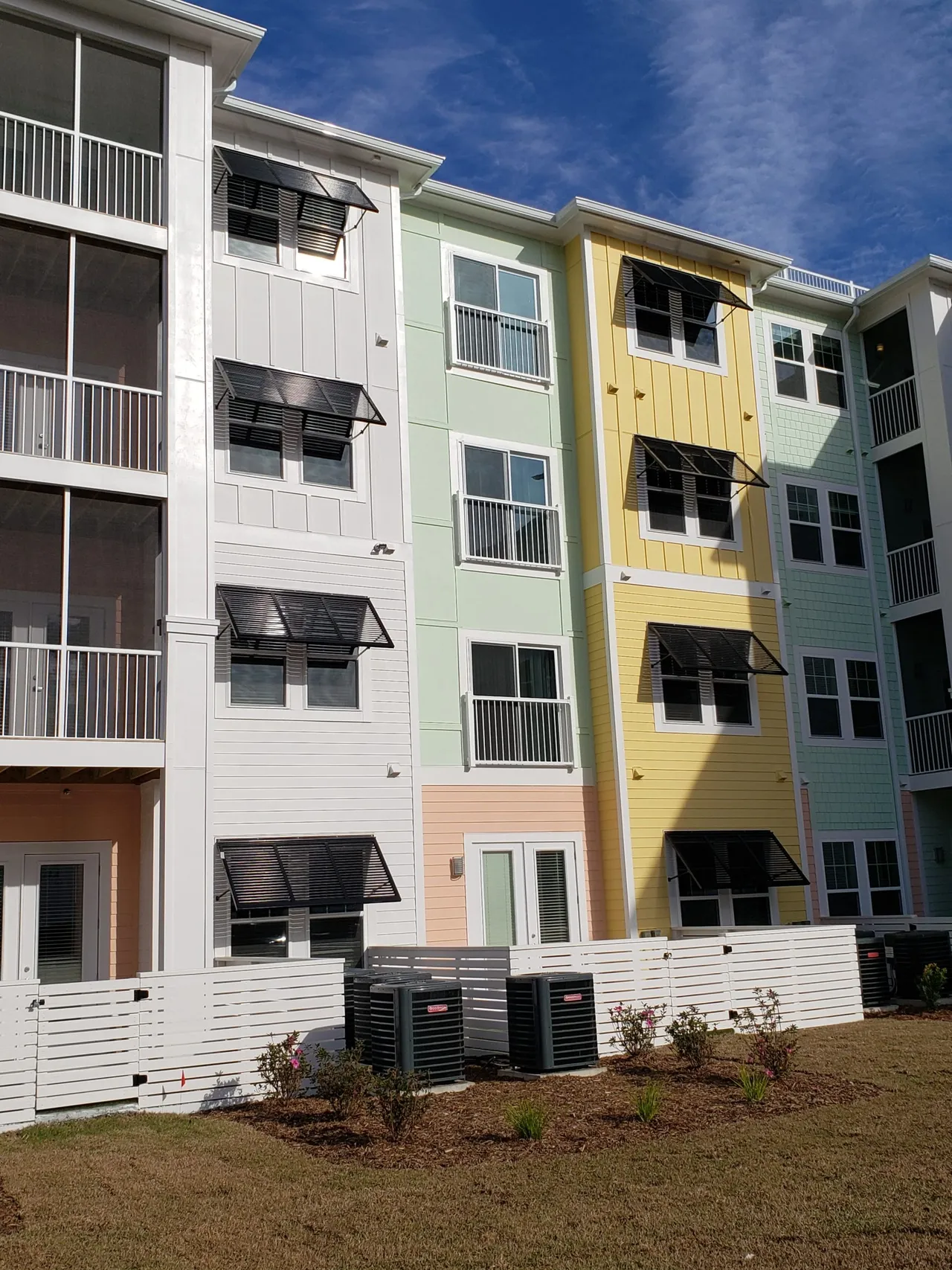 Colorful multi-story apartment complex with black shutters and balconies