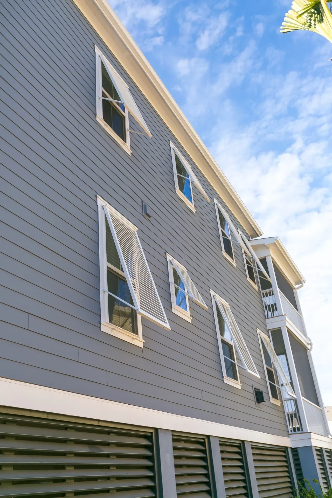 Multi-story building with white-trimmed windows and gray siding against blue sky