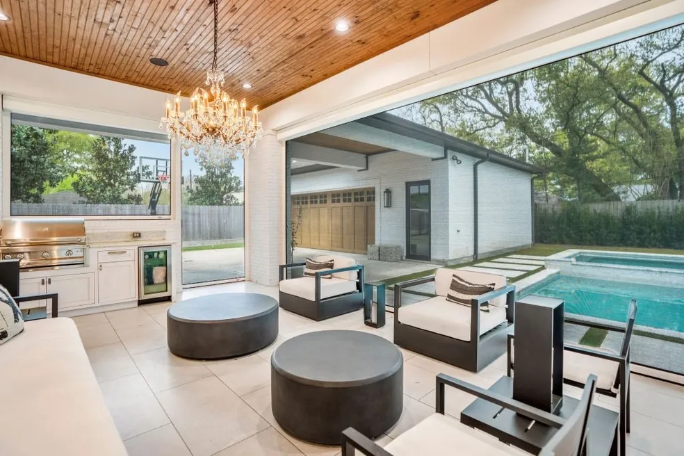 Luxurious indoor-outdoor living space with pool, kitchen, and elegant chandelier