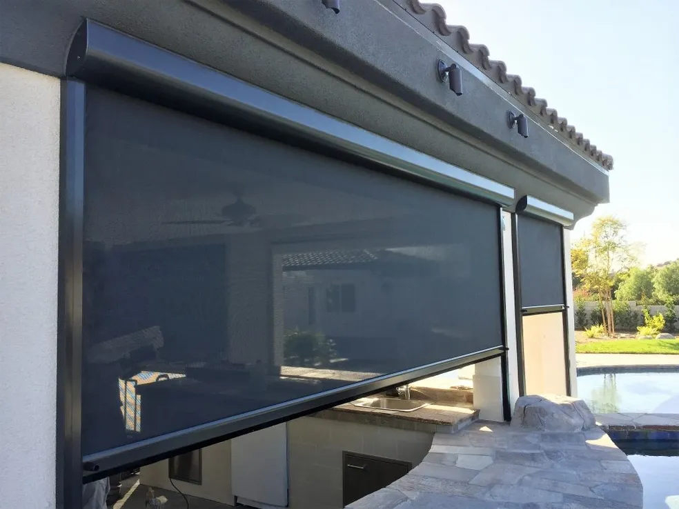 Outdoor patio with retractable gray screen and pool in background